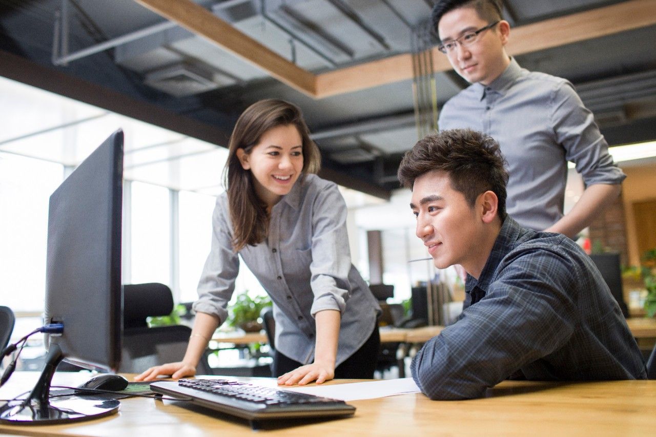 Two men and a woman looking at a computer
